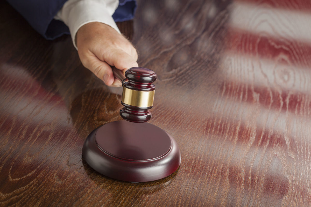 Judge slams his gavel and American flag table reflection.