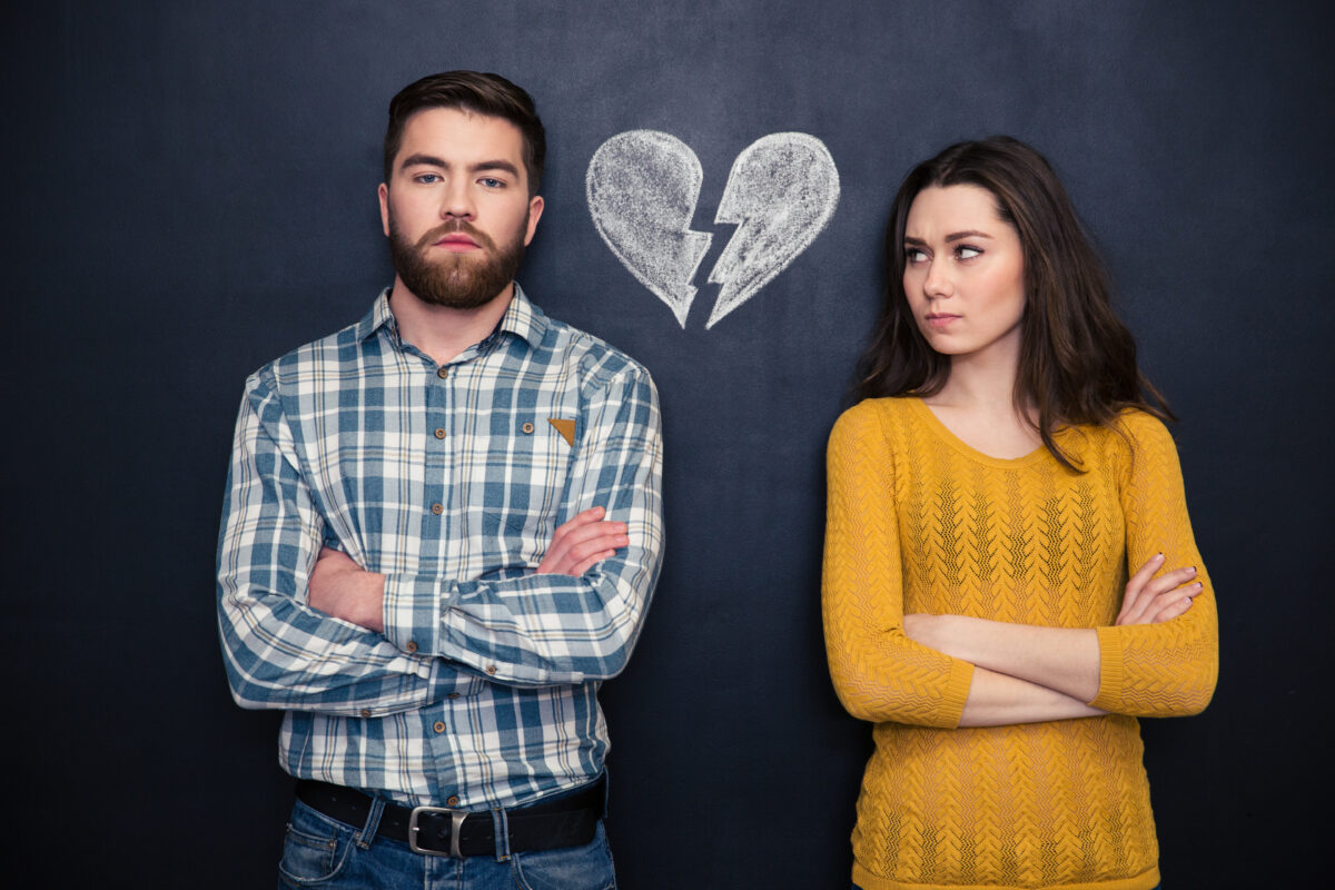 young couple standing separately with hands folded over a blackboard background