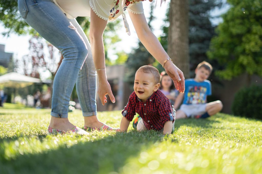 A mother playing with her child outdoors.