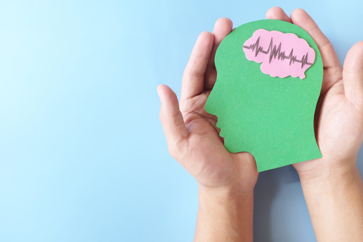 Hands holding a human head profile cutout with a healthy brain.