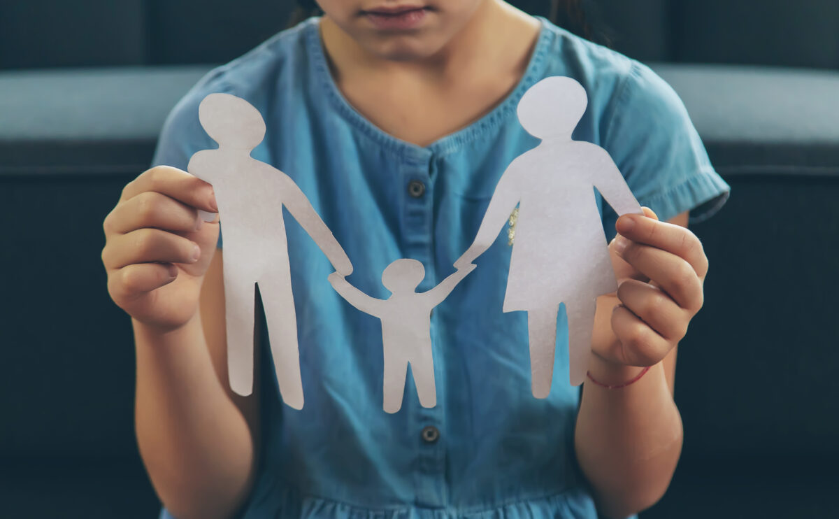 Child with a paper family in his hands. The concept of divorce, custody, and child abuse.