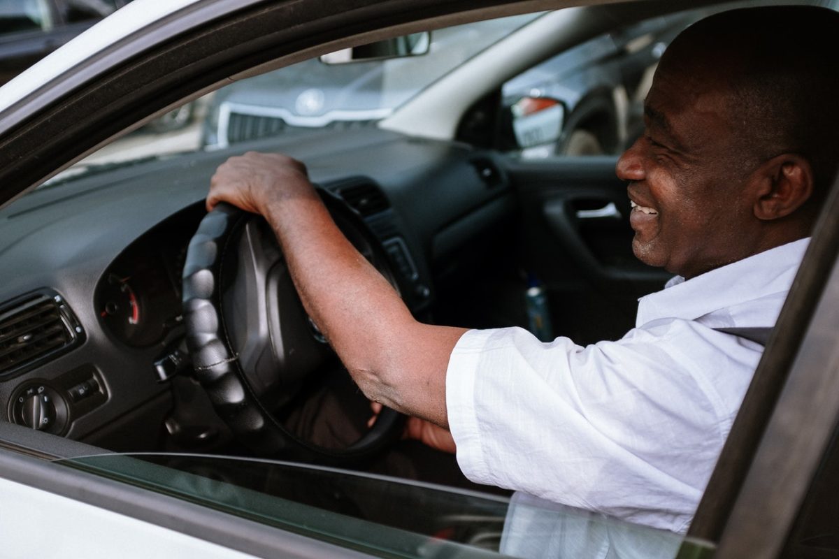 An African American man smiling inside his car.