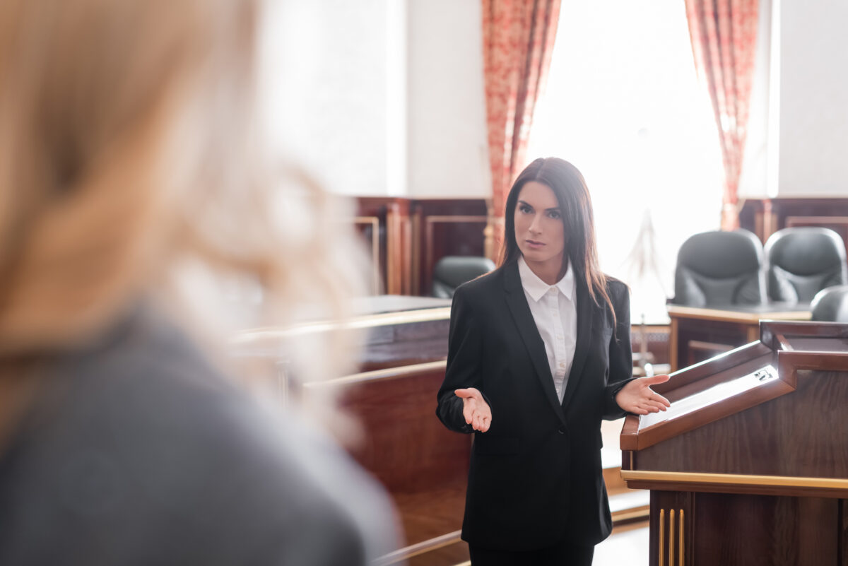 prosecutor pointing with hands while talking to blurred witness in courtroom