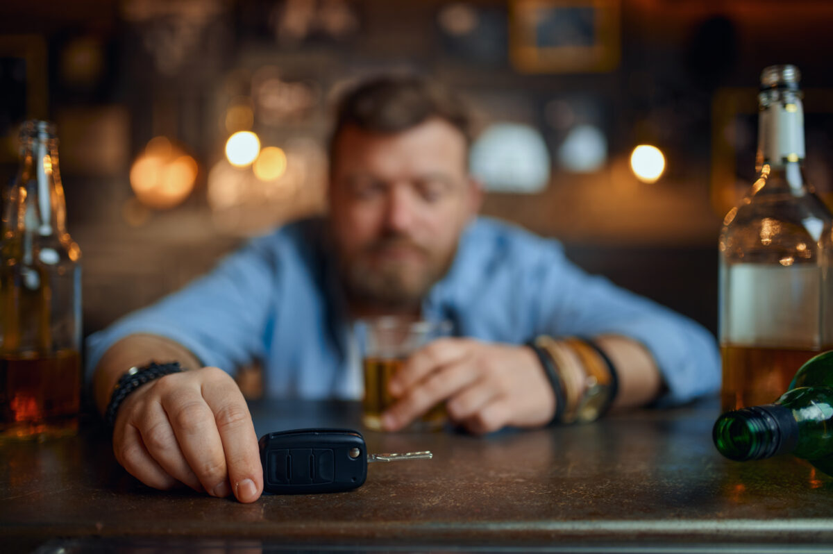 Drunk man with a car key is sitting at the counter in the bar.