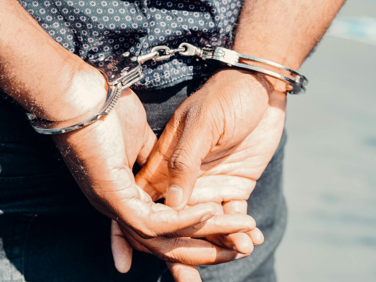 A man's hands in handcuffs, positioned behind his back.