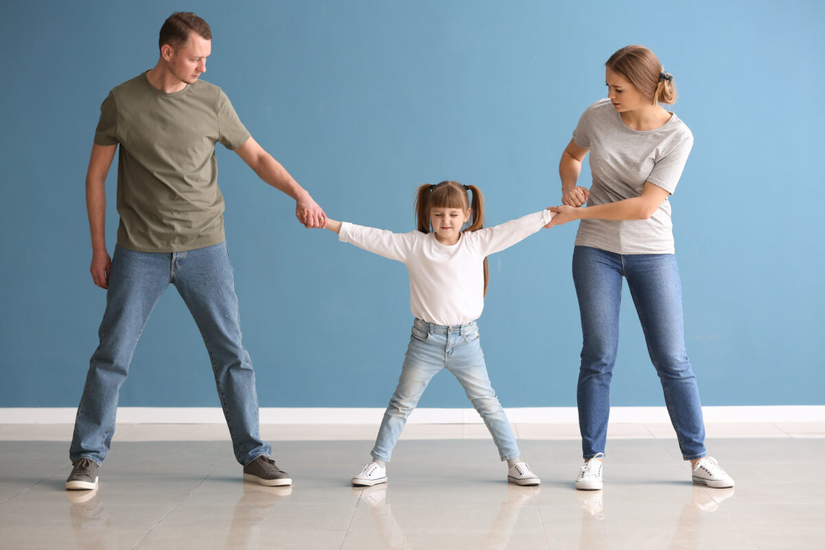 Divorced parents arguing about child custody against color wall