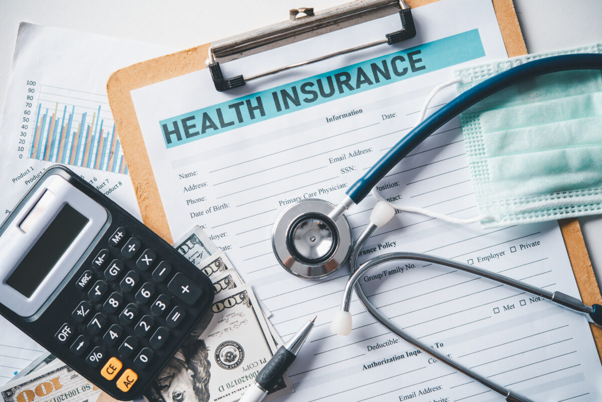 A stethoscope and calculator placed on health insurance documents.