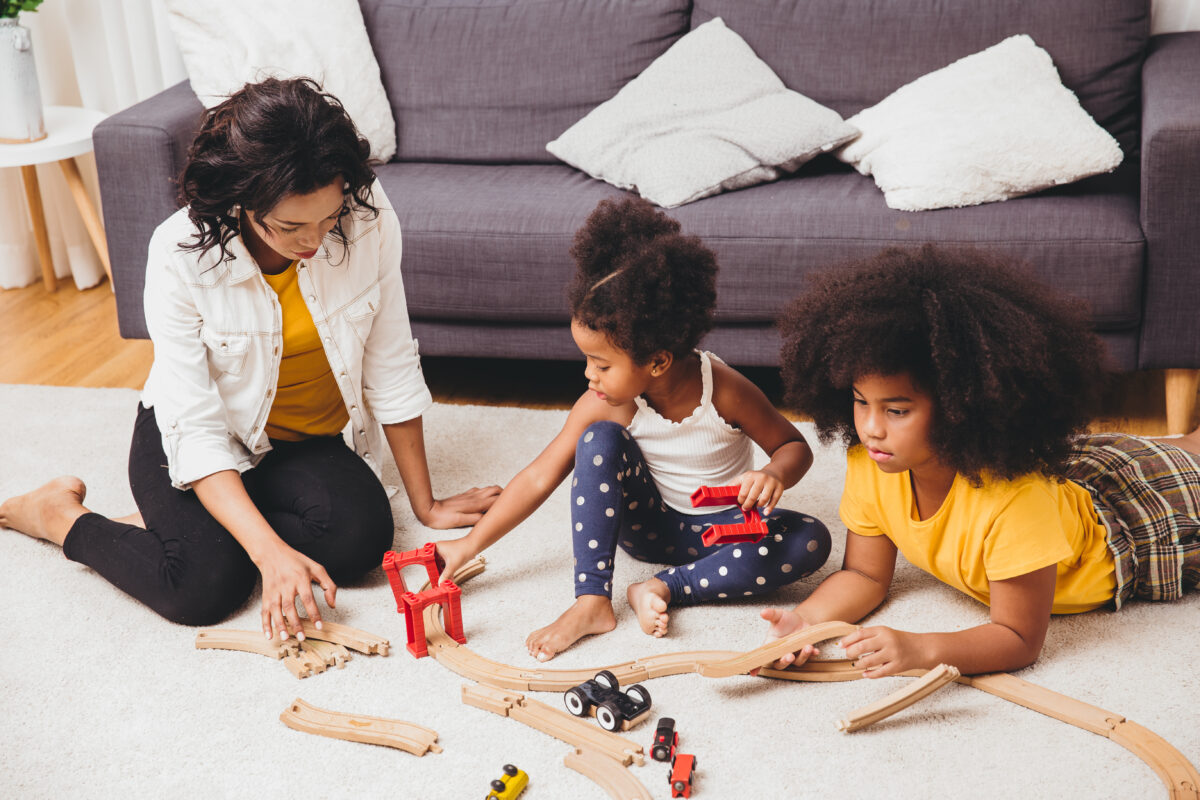 Mother playing with children learning to solve puzzle toys at home apartment.