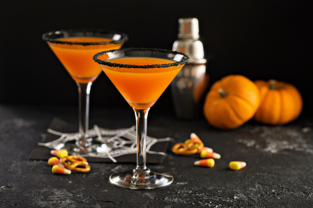 A Halloween or fall cocktail, a pumpkintini with a black rim, resembling a pumpkin martini.