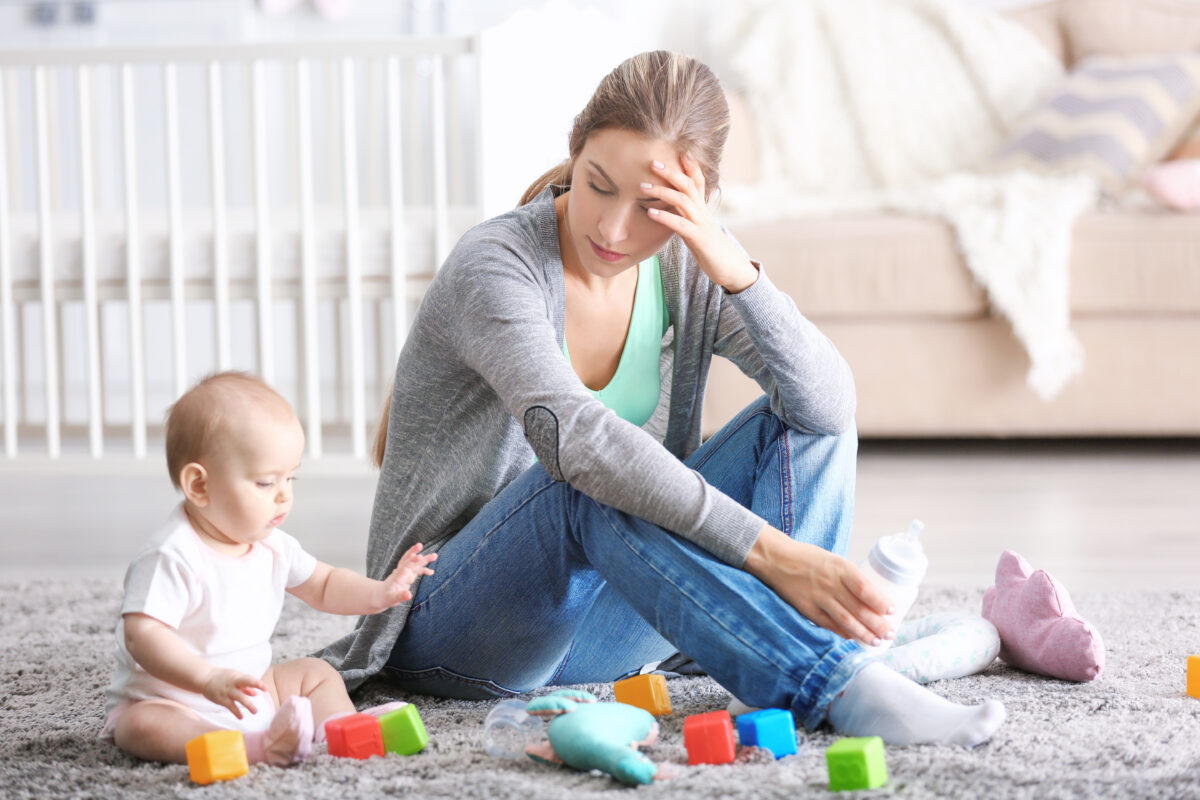 Depressed young woman with cute baby at home