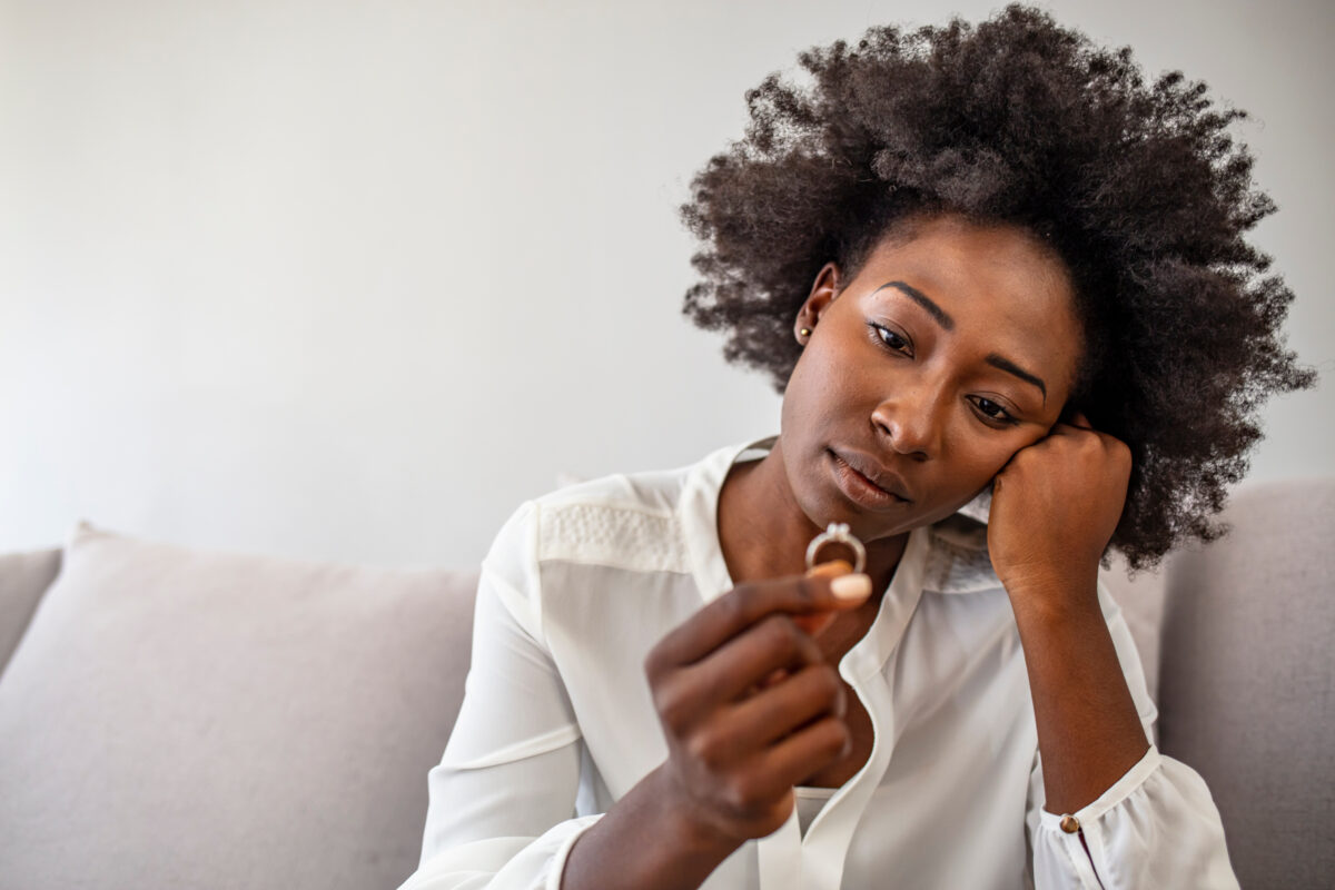 Unhappy woman holding wedding ring close up