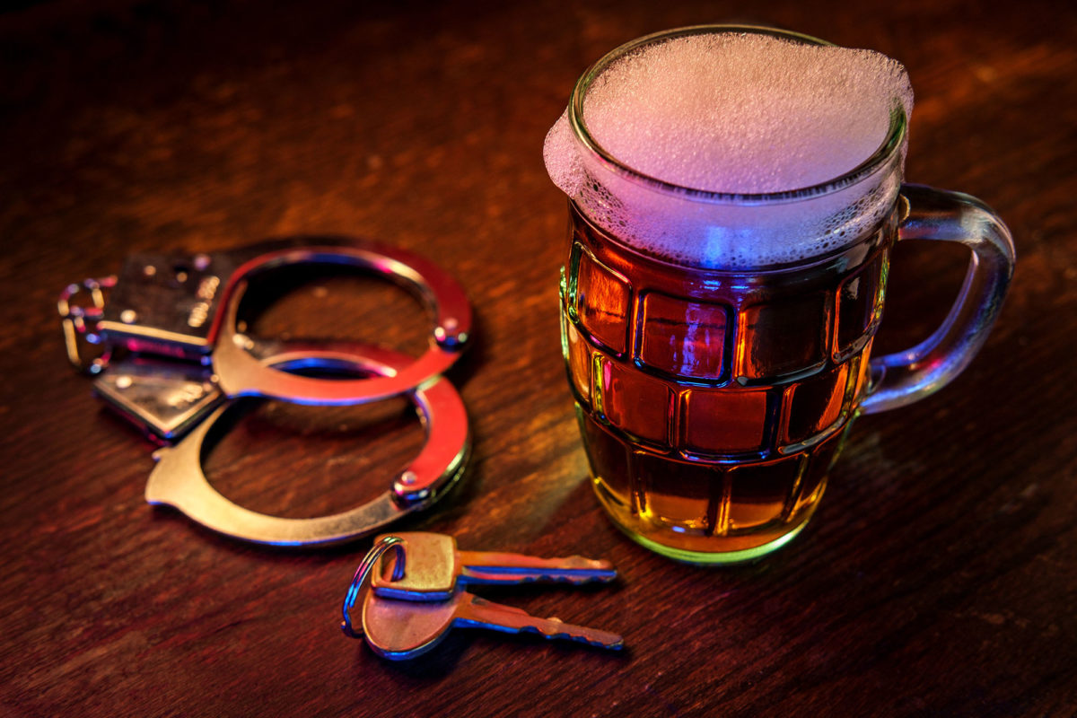 Mug of frothy beer with handcuffs and keys symbolizing drunk driving arrest