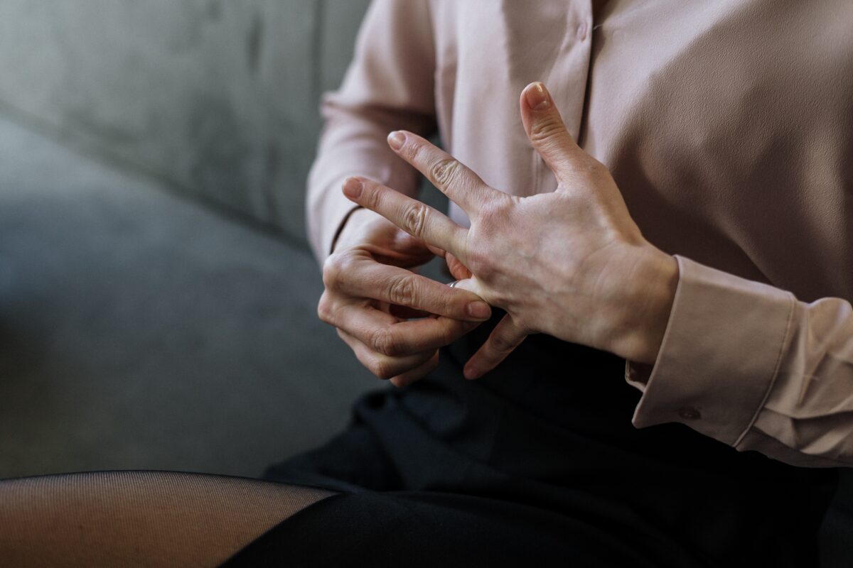 A seated woman is taking off her wedding ring.