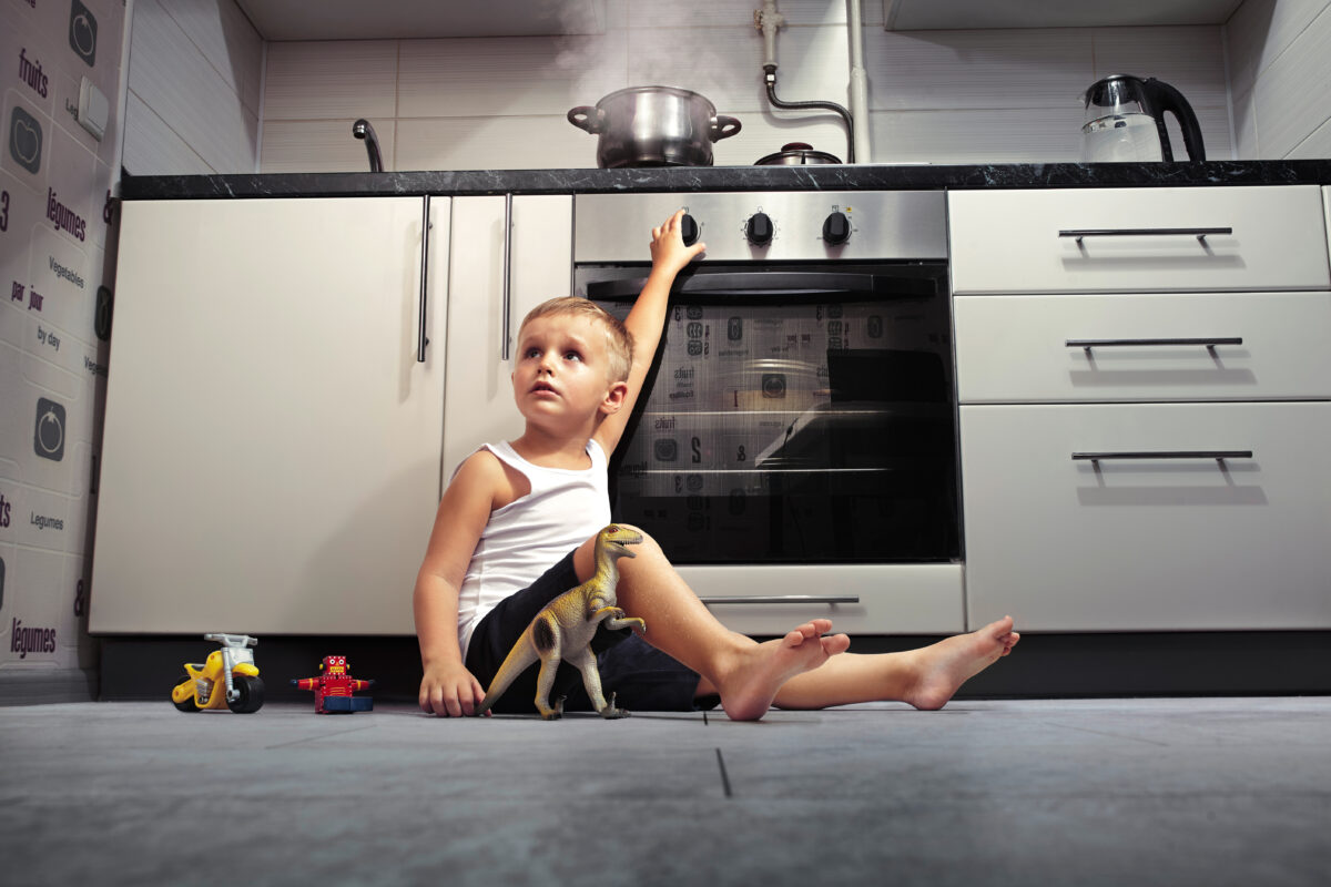 accident prevention. An unattended child playing in the kitchen with a gas stove.